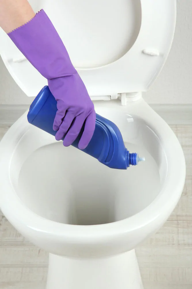 applying toilet bowl cleaner under rim for deep clean